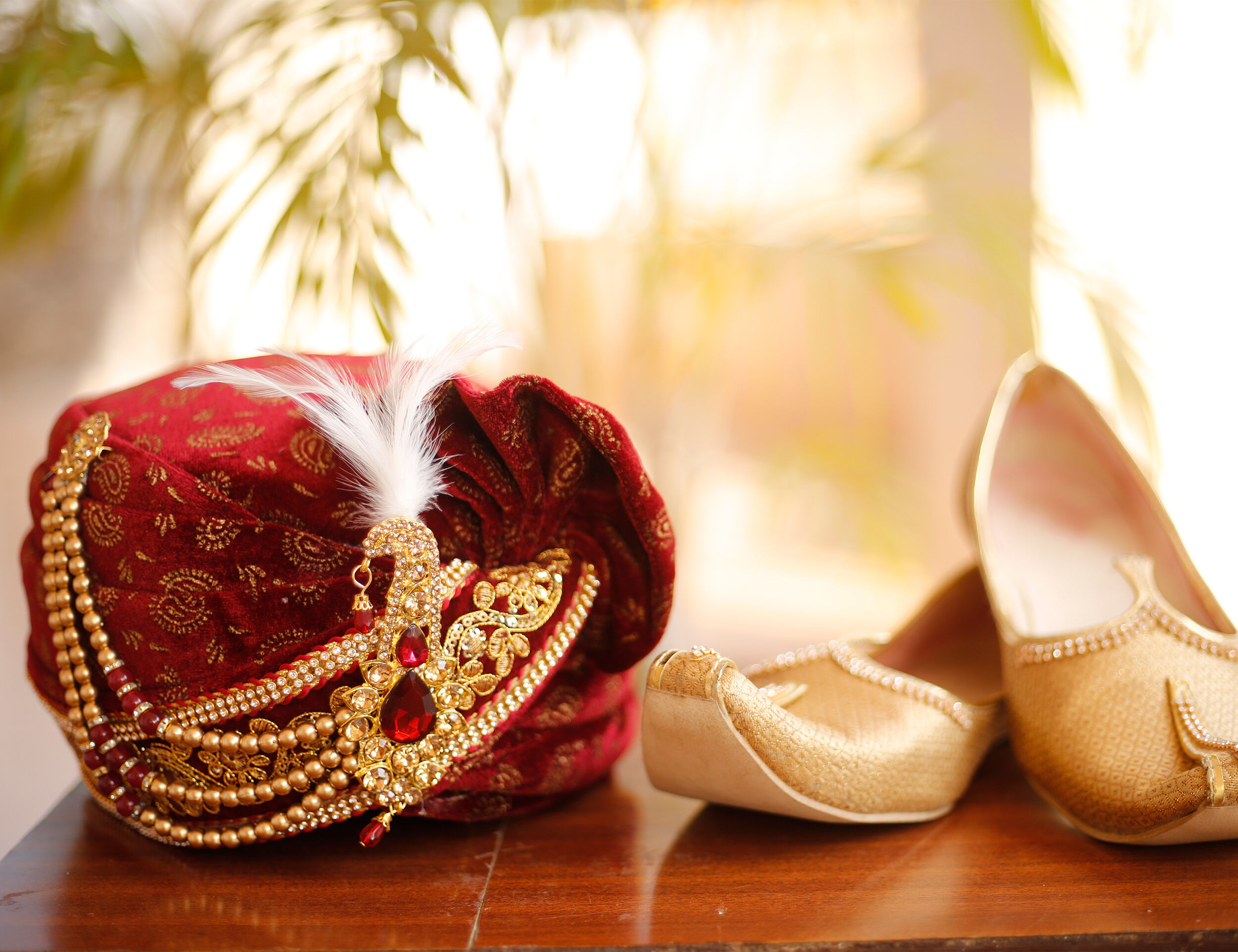 Red safa adorned with golden pearl chain and feather, styled with golden juttis.